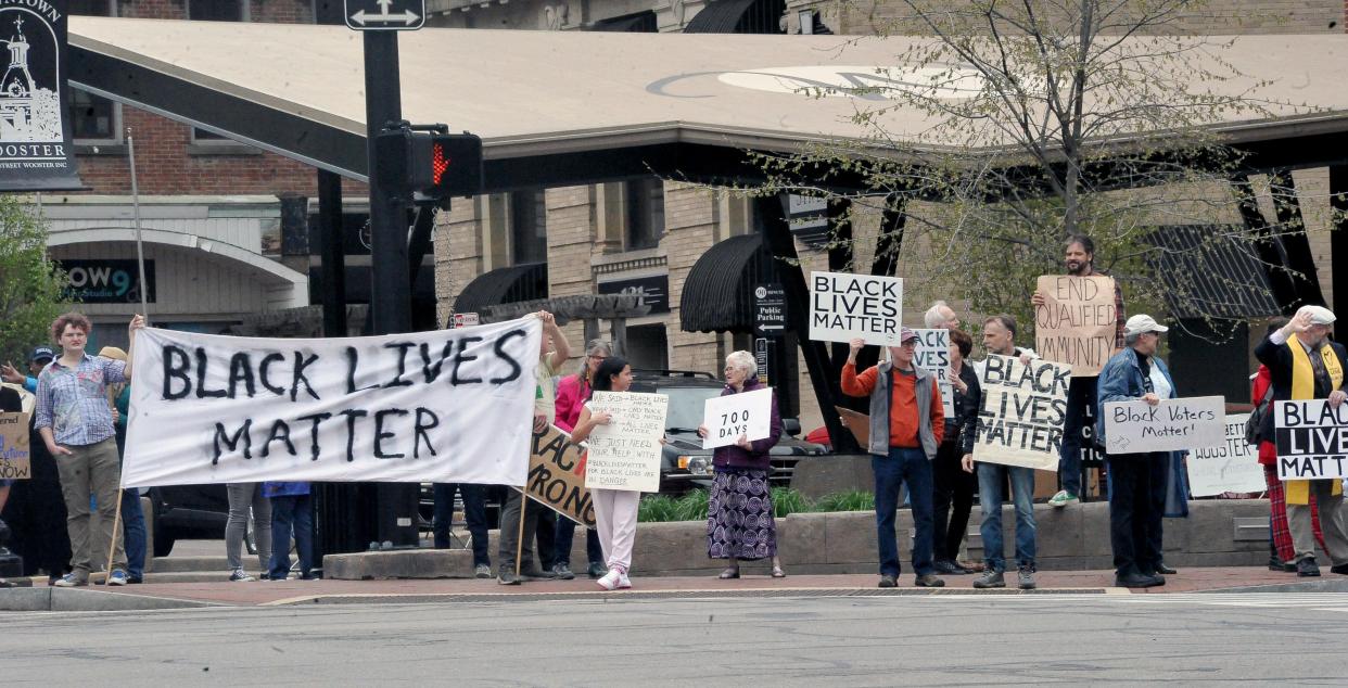 Approximately 50 demonstrators hold signs and wave to passersby in downtown Wooster Sunday, the 700th consecutive day of protests since George Floyd's death.