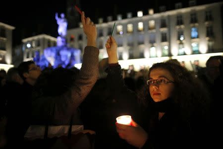 A woman holds a candle to pay tribute during a gathering at the Place Royal in Nantes January 7, 2015, following a shooting by gunmen at the offices of weekly satirical magazine Charlie Hebdo. REUTERS/Stephane Mahe