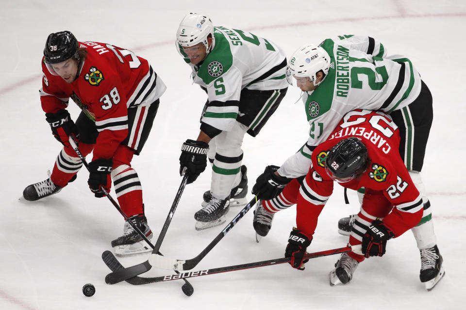 Chicago Blackhawks left wing Brandon Hagel (38) and teammate Ryan Carpenter (22) battle for the puck with Dallas Stars defenseman Andrej Sekera (5) and left wing Jason Robertson (21) during the second period of an NHL hockey game Tuesday, April 6, 2021, in Chicago. (AP Photo/Jeff Haynes)