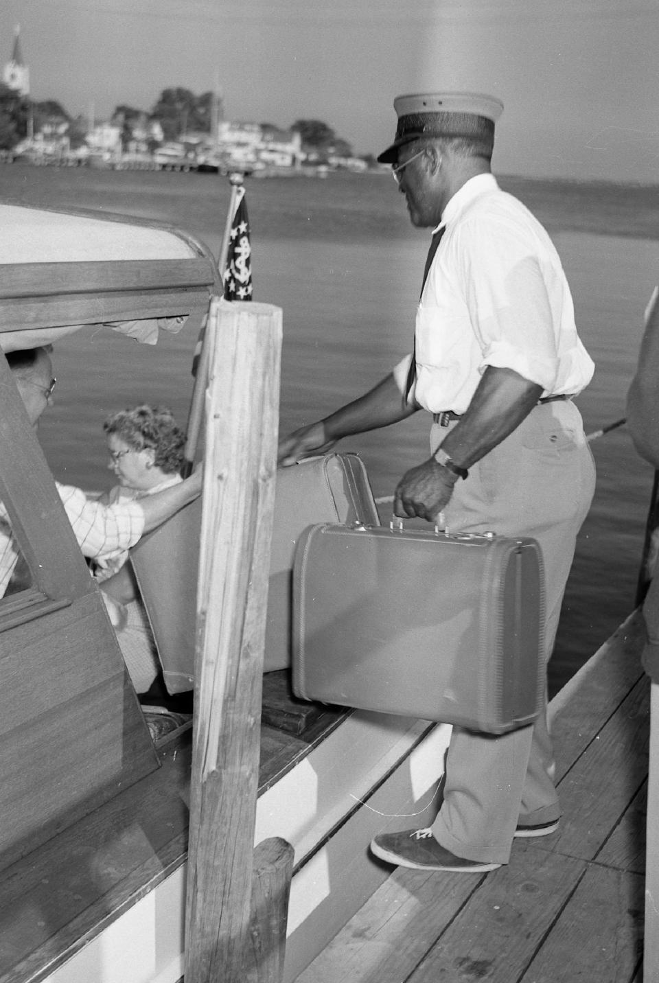 A porter from The Grand Hotel handing luggage to Mackinac Island visitors taking Shepler's Ferry circa 1950. The luggage handling process hasn't changed much over the past 75 years.