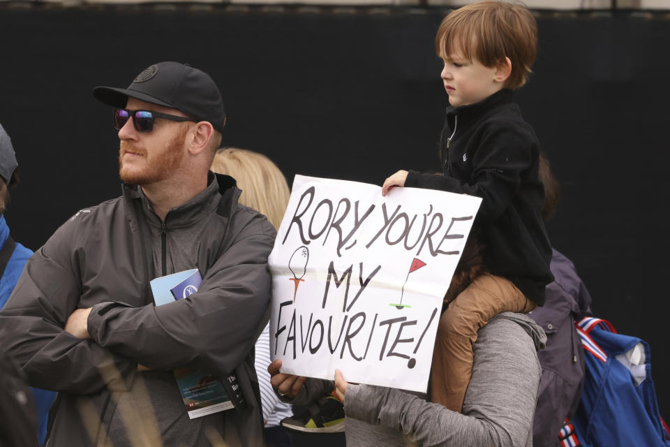 A young Rory McIlroy fan holds up a note as he watches him play near the 6th hole during a practice round for the British Open Golf Championships at the Royal Liverpool Golf Club in Hoylake, England, Tuesday, July 18, 2023. The Open starts Thursday, July 20. (AP Photo/Peter Morrison)