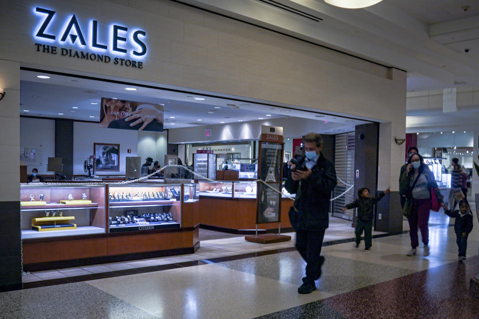 Shoppers walk past a Zales jewelry store inside the Kings Plaza Mall, Tuesday Oct. 20, 2020, in New York. The coronavirus pandemic is transforming holiday hiring this year, with companies starting hiring earlier and offering extra safety protocols. Zales plans to hire 4,000 holiday workers. (AP Photo/Bebeto Matthews)