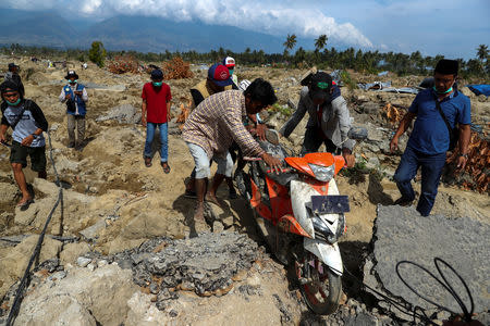 Villagers drag a motorcycle in an area after an earthquake hit Petobo neighbourhood in Palu, Indonesia, October 6, 2018. REUTERS/Athit Perawongmetha