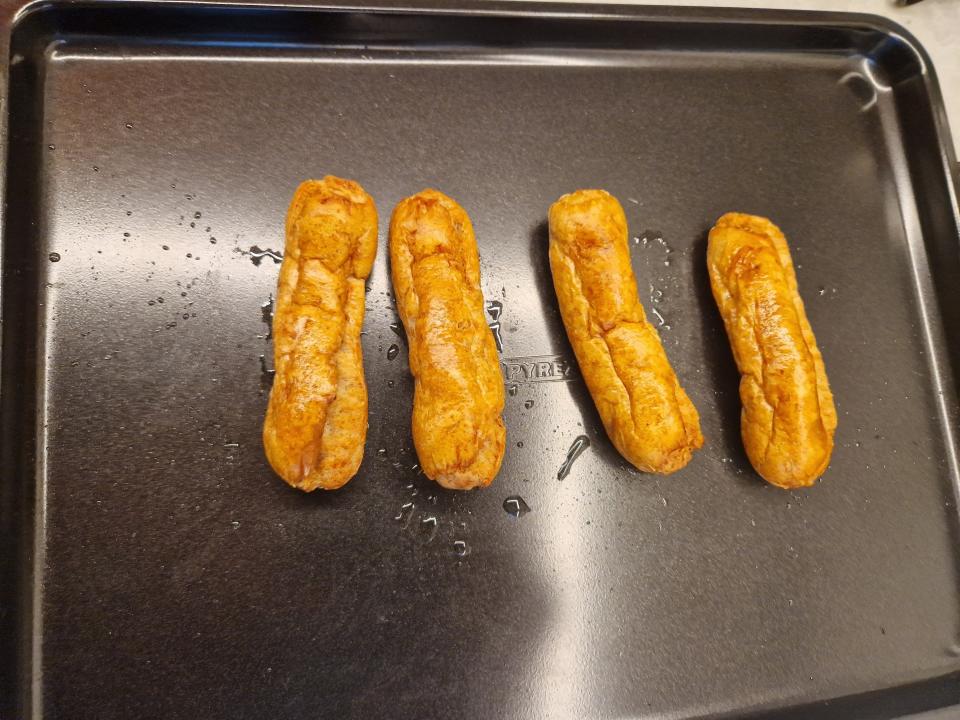 four shriveled sausage links on a baking tray