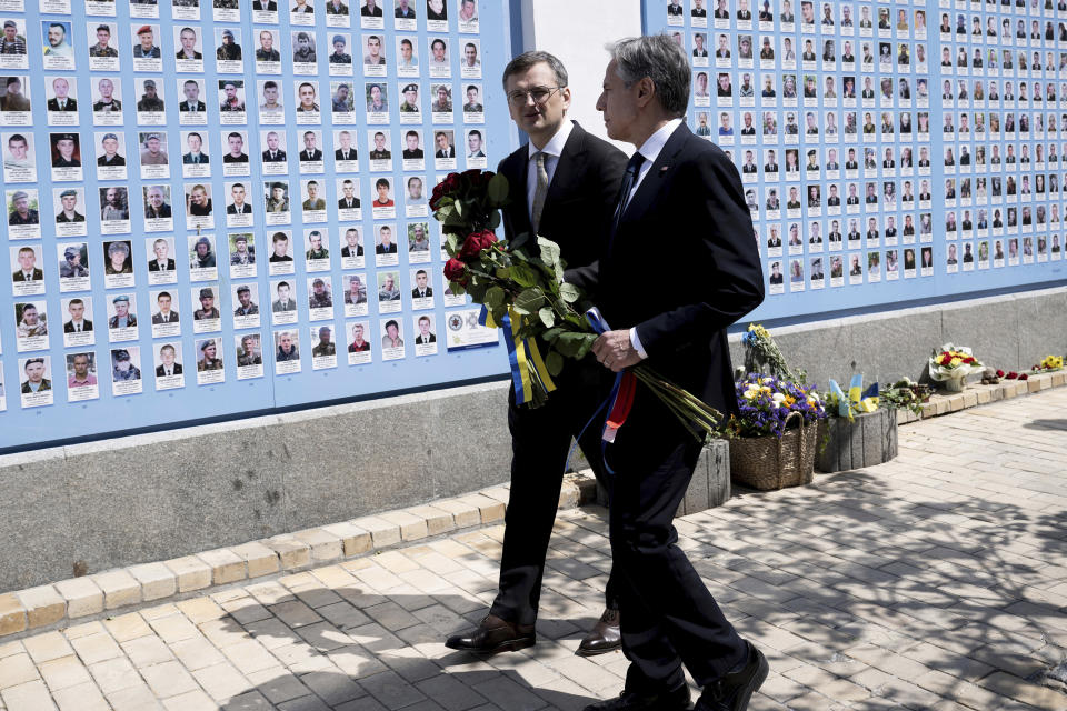 US Secretary of State Antony Blinken, right, and Ukrainian Foreign Minister Dmytro Kuleba hold a bunch of roses as they walk at the Memory Wall of Fallen Defenders of Ukraine outside the Saint Michael's Golden Domed Monastery in Kyiv on Wednesday, May 15, 2024. (Brendan Smialowski/Pool Photo via AP)