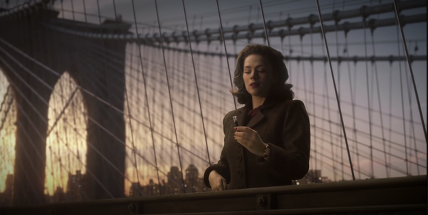 Agent Peggy Carter from "Agent Carter" standing on the side of the Brooklyn Bridge with a vial of liquid