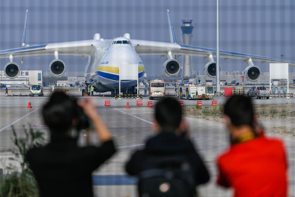 People look on as workers load 81.3 tons of medical supplies onto an Antonov-225 