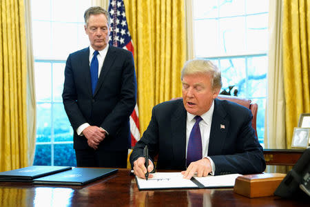 U.S. President Donald Trump, flanked by U.S. Trade Representative Robert Lighthizer, signs a directive to impose tariffs on imported washing machines in the Oval Office at the White House in Washington, U.S. January 23, 2018. REUTERS/Jonathan Ernst