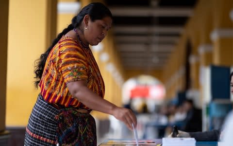 A woman casts her vote at a polling station, in San Juan Sacatepequez, - Credit: Santiago Billy/AP