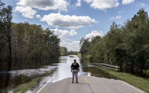 A Pender County Sheriff looks out over a flooded road - Credit: Alex Wroblewski/Bloomberg