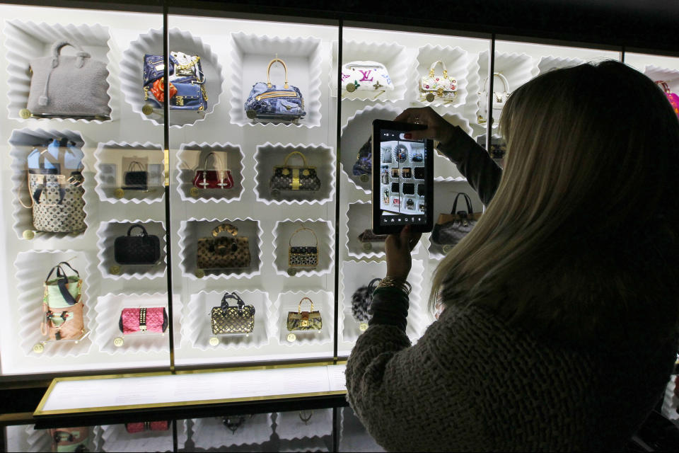 A visitor takes a picture of fashion creations displayed at the Louis Vuitton-Marc Jacobs exhibit in the Art Decoratifs Museum in Paris, Thursday, March 8, 2012. (AP Photo/Francois Mori)