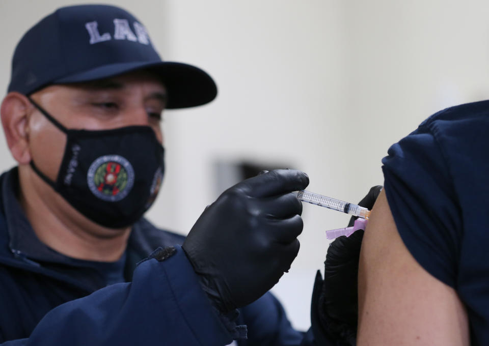 LOS ANGELES, CALIFORNIA - JANUARY 29: A Los Angeles Fire Department (LAFD) firefighter receives a COVID-19 vaccination dose from firefighter Michael Perez at a fire station on January 29, 2021 in Los Angeles, California. LAFD has recorded a ‘sharp decline’ in coronavirus cases after firefighters began receiving the vaccine shots on December 28. (Photo by Mario Tama/Getty Images)