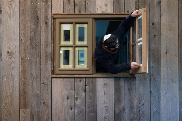 An employee removes tape from a window in a shepherd’s hut in the workshop of Plankbridge 