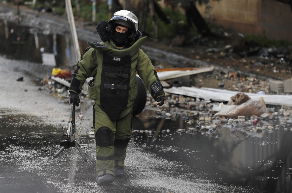 A Lebanese police bomb disposal expert carries equipment before destroy an unexploded hand grenade that was throw by protesters on Thursday night inside the parking of an official government office, during a protest against deteriorating living conditions and strict coronavirus lockdown measures, in Tripoli, Lebanon, Friday, Jan. 29, 2021. (AP Photo/Hussein Malla)