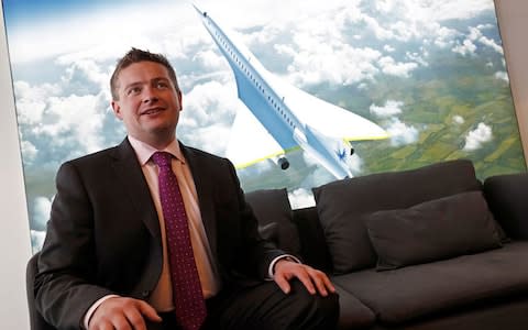 Blake Scholl and behind him an image of the 55-seat Boom aircraft - Credit: Getty