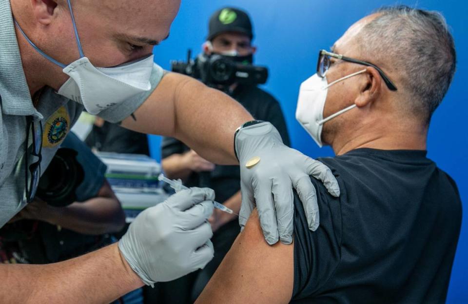 Miami-Dade Fire Rescue’s Javier Crespo administers the Pfizer-BioNTech COVID-19 vaccine to Carlos Dennis on January 4, 2021, at the Christine E. Lynn Rehabilitation Center at Jackson Memorial Hospital where people over 65 are being vaccinated.