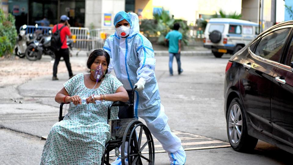 Eine mit dem Coronavirus infizierte Patientin sitzt im Rollstuhl und wird in das Kolkata Medical College Hospital eingeliefert.