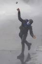 An anti-government protester hurls a stone at police deployed outside Congress, as lawmakers debate a reform bill promoted by Argentine President Javier Milei in Buenos Aires, Argentina, Wednesday, June 12, 2024. (AP Photo/Natacha Pisarenko)