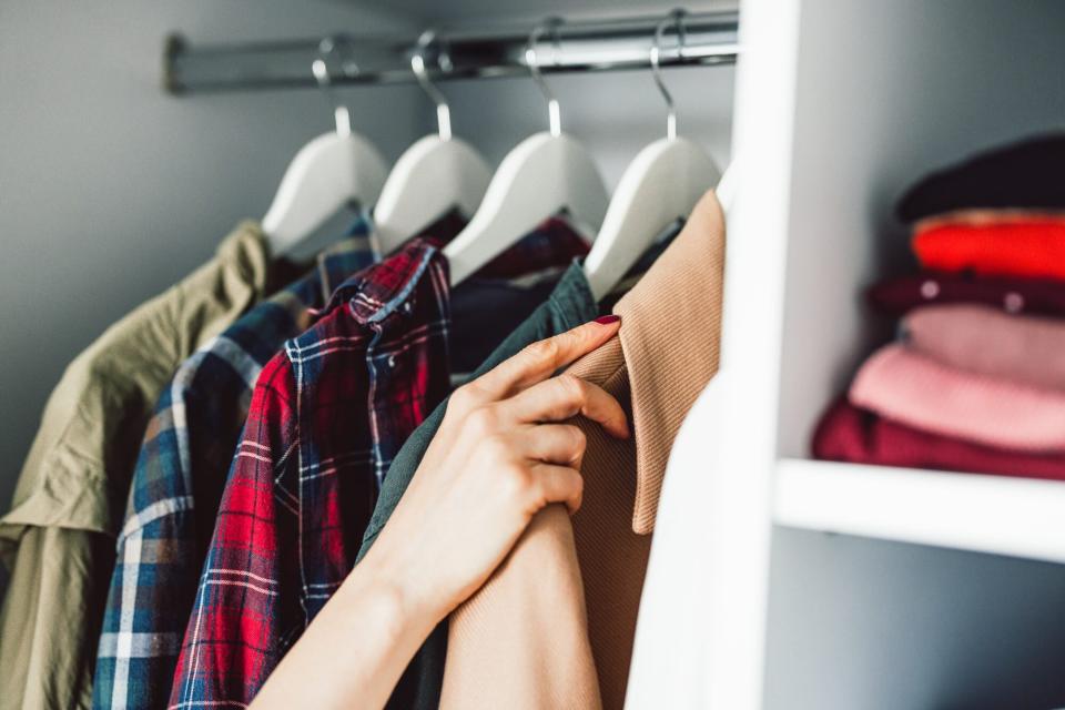 coats in closet with hand choosing one
