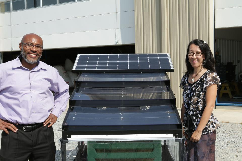 Husband and wife team, Klein and Reiko Ileleji, pose near a solar-powered crop drying device that could reduce post-harvest losses and add value to smallholders in developing countries. The device utilizes high temperatures, high air-flow rate and low humidity features to better dry crops. Klein and Reiko founded JUA Technologies International LLC to further develop and commercialize the technology.