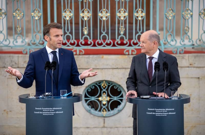 German Chancellor Olaf Scholz (R) stands next to French President Emmanuel Macron during the press conference of the French-German Council of Ministers in front of Schloss Meseberg, the German government's guest house.  Michael Kappeler/dpa