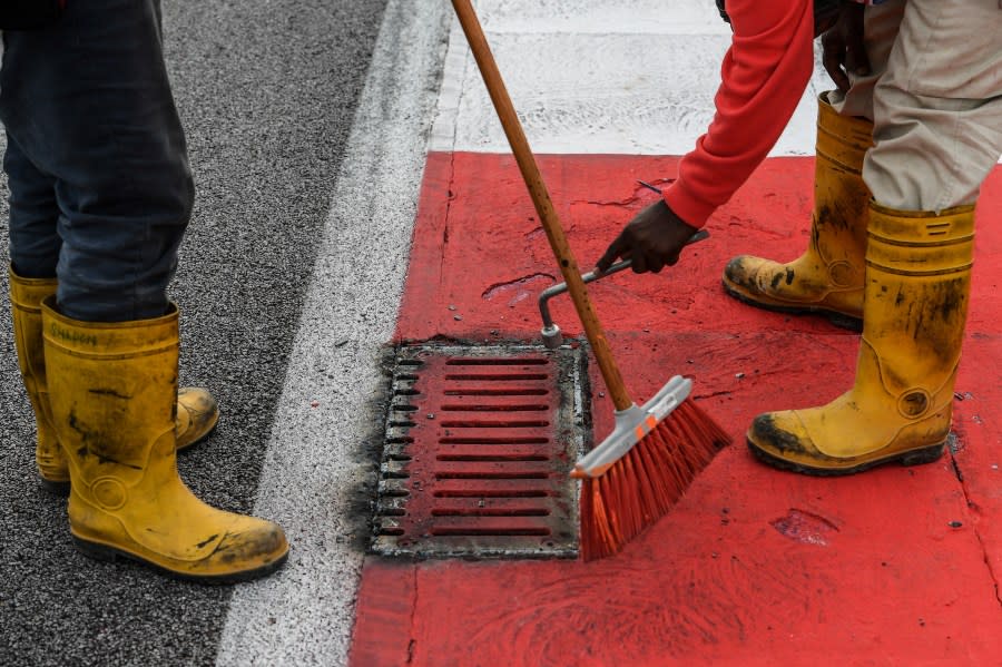 Workers repair a drain cover after Haas F1’s French driver Romain Grosjean suffered a frightening tyre explosion during the second practice session of the Formula One Malaysia Grand Prix in Sepang on September 29, 2017. / AFP PHOTO / MOHD RASFAN (Photo credit should read MOHD RASFAN/AFP via Getty Images)