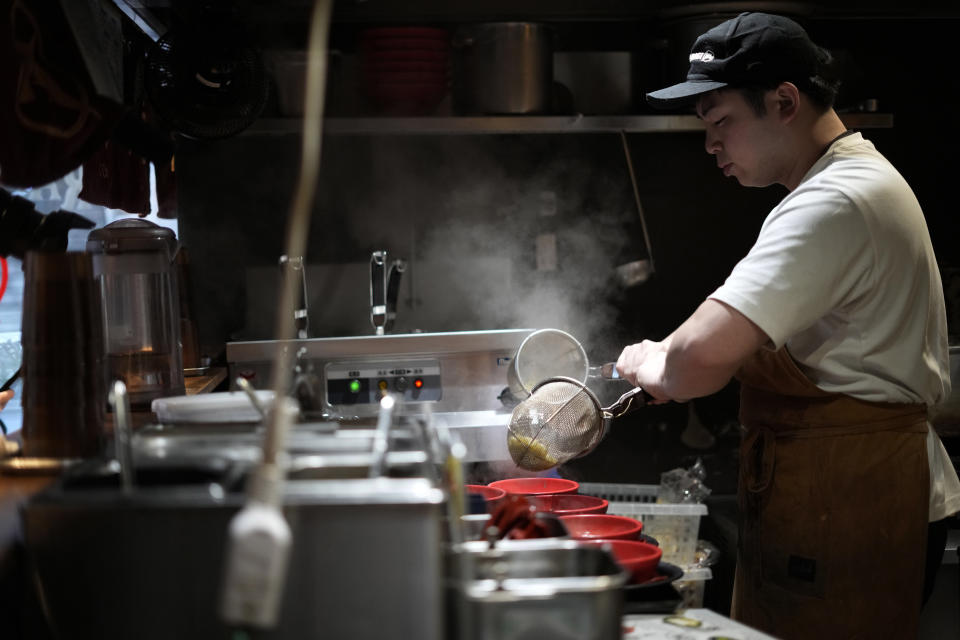 A chef cooks noodle for participants of Tokyo Ramen Tours at Nagi, which offers "Fukuoka fusion," type ramen at Shibuya district on April 2, 2024, in Tokyo. (AP Photo/Eugene Hoshiko)