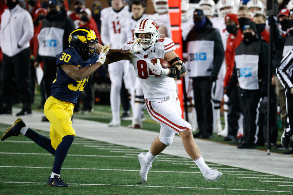 Nov 14, 2020; Ann Arbor, Michigan, USA; Wisconsin Badgers tight end Jake Ferguson (84) stiff arms Michigan Wolverines defensive back Daxton Hill (30) in the second half at Michigan Stadium. <em>Rick Osentoski-USA TODAY Sports</em>