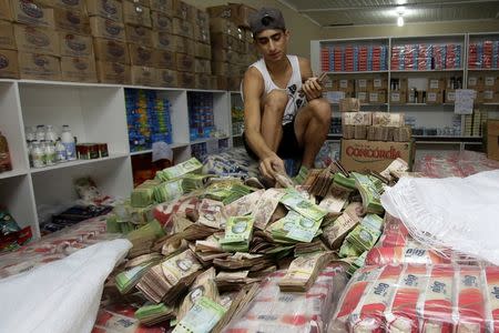 A man counts Venezuelan bolivar notes at a store that sells staple items and food in Pacaraima, Brazil August 3, 2016.REUTERS/William Urdaneta
