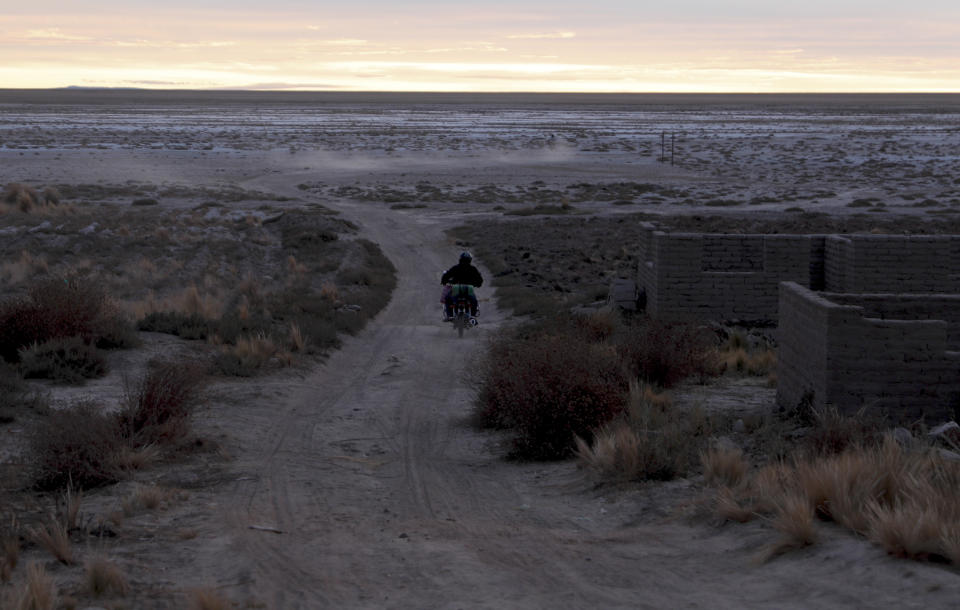 A resident drives his motorcycle on a dirt path alongside the salt-crusted former shoreline of Lake Poopo, in Punaca, Bolivia, Sunday, May 23, 2021. For many generations, the homeland of the Uru wasn't land at all: It was the brackish waters of Lake Poopo. Now what was Bolivia's second-largest lake is gone. It dried up about five years ago, victim of shrinking glaciers, water diversions for farming and contamination. (AP Photo/Juan Karita)