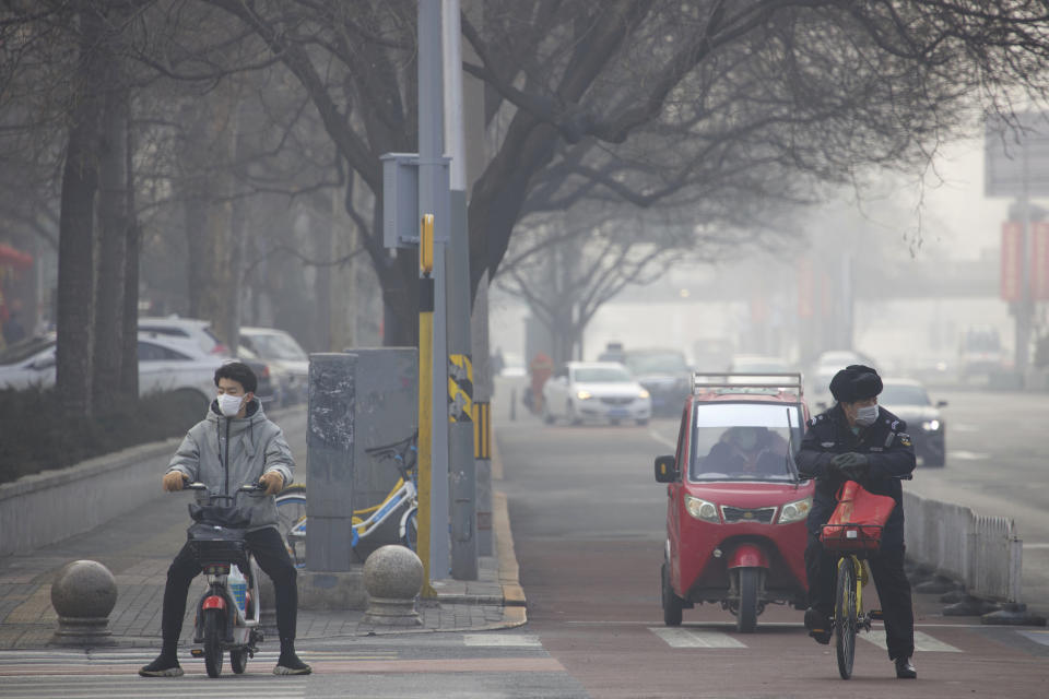 Residents wear masks on a street of Beijing, China Tuesday, Feb. 11, 2020. China's daily death toll from a new virus topped 100 for the first time and pushed the total past 1,000 dead, authorities said Tuesday after leader Xi Jinping visited a health center to rally public morale amid little sign the contagion is abating. (AP Photo/Ng Han Guan)