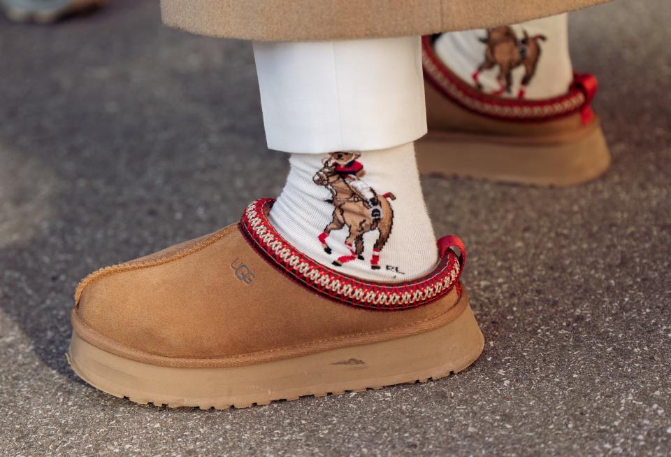 Close-up of somewhere wearing brown ugg slipper shoes with a red trim