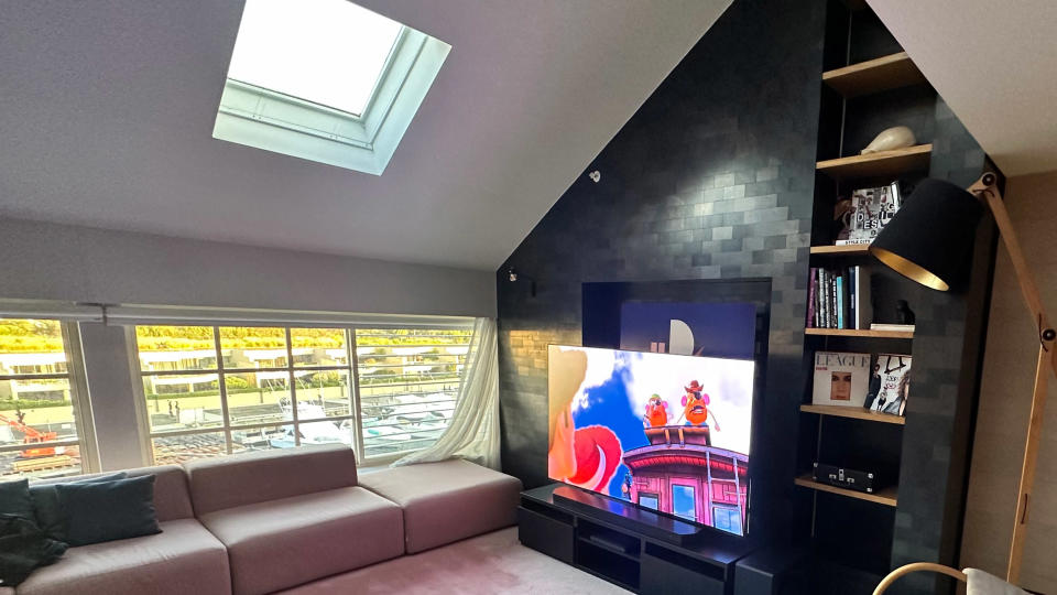 Samsung S95D on a TV bench in a hotel room, with sunlight coming into the room through windows and a skylight