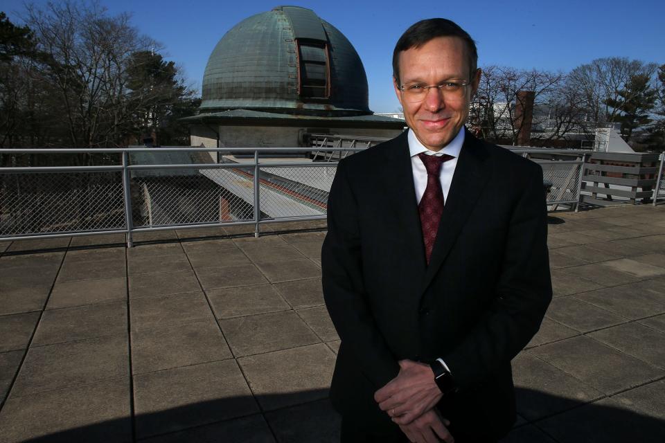Avi Loeb is seen posing waist upwards on the roof of some observatory. He's wearing a suit and smiling at the camera.