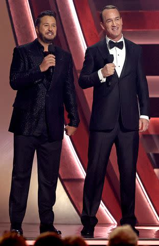 <p>Terry Wyatt/Getty</p> Luke Bryan and Peyton Manning speak onstage during the 57th Annual CMA Awards