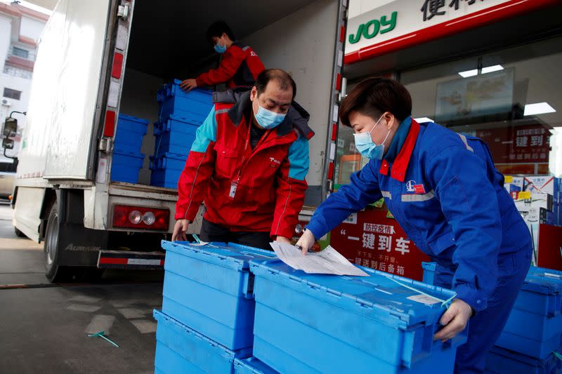 FILE PHOTO: Workers unload groceries at a Sinopec gas station in Beijing where customers can buy supplies while they refuel
