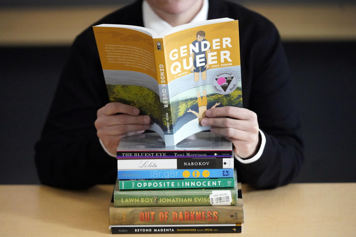 FILE - Amanda Darrow, director of youth, family and education programs at the Utah Pride Center, poses with books that have been the subject of complaints from parents on Dec. 16, 2021, in Salt Lake City. With legislators in Florida barring even the mention of being gay in classrooms and similar restrictions being considered in other states, books with LGBTQ+ themes remain the most likely targets of bans or attempted bans at public schools and libraries around the country, according to a new report Monday, April 24, 2023. Maia Kobabe’s graphic memoir “Gender Queer,” was the most “challenged” book of 2022, the second consecutive year it has topped the list. (AP Photo/Rick Bowmer, File)