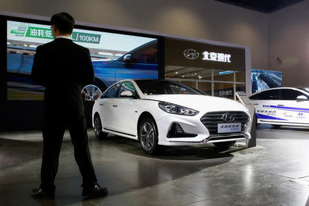 A man stands next to a Sonata hybrid at a booth of Beijing Hyundai Motor, the joint venture between South Korea's Hyundai Motor and China's BAIC Motor, during an energy-saving and new energy vehicles expo in Beijing, China October 18, 2018. REUTERS/Thomas Peter