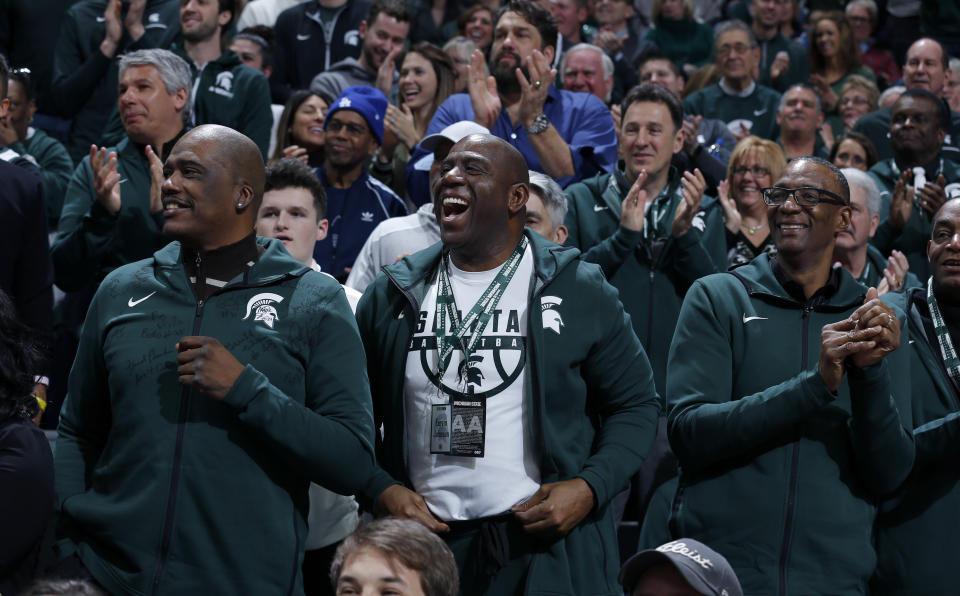 Former players on Michigan State's 1979 national championship team, including Magic Johnson, center, Jay Vincent, left, and Greg Kelser, right, react during the first half of an NCAA college basketball game against Minnesota, Saturday, Feb. 9, 2019, in East Lansing, Mich. (AP Photo/Al Goldis)