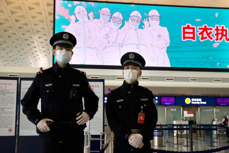 Policías usando mascarillas para protegerse de la propagación del nuevo coronavirus, de guardia en el aeropuerto internacional de Wuhan-Tianhe en Wuhan, en la provincia de Hubei, en el centro de China, el 8 de abril de 2020.