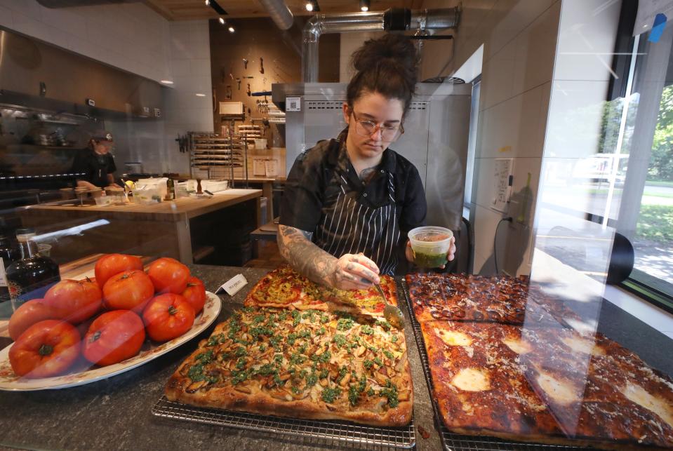 Chef Taylor Wilde puts on the finishing touches of pesto on a seasonal pizza as she prepares to open Wildflour for the lunch hour.