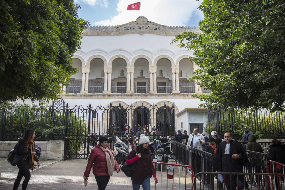 People walk in front of the Tunis Palace of Justice in Tunis, Tuesday, Jan.29, 2019. More than 40 people have been summoned to face trial over Tunisia's deadliest attack in a Mediterranean resort in 2015. The trial reopened on Tuesday in Tunis, more than 3-1/2 years after the attack on the Imperial Hotel in the beach resort of Sousse left 38 people dead, mostly British tourists.(AP Photo/Hassene Dridi)