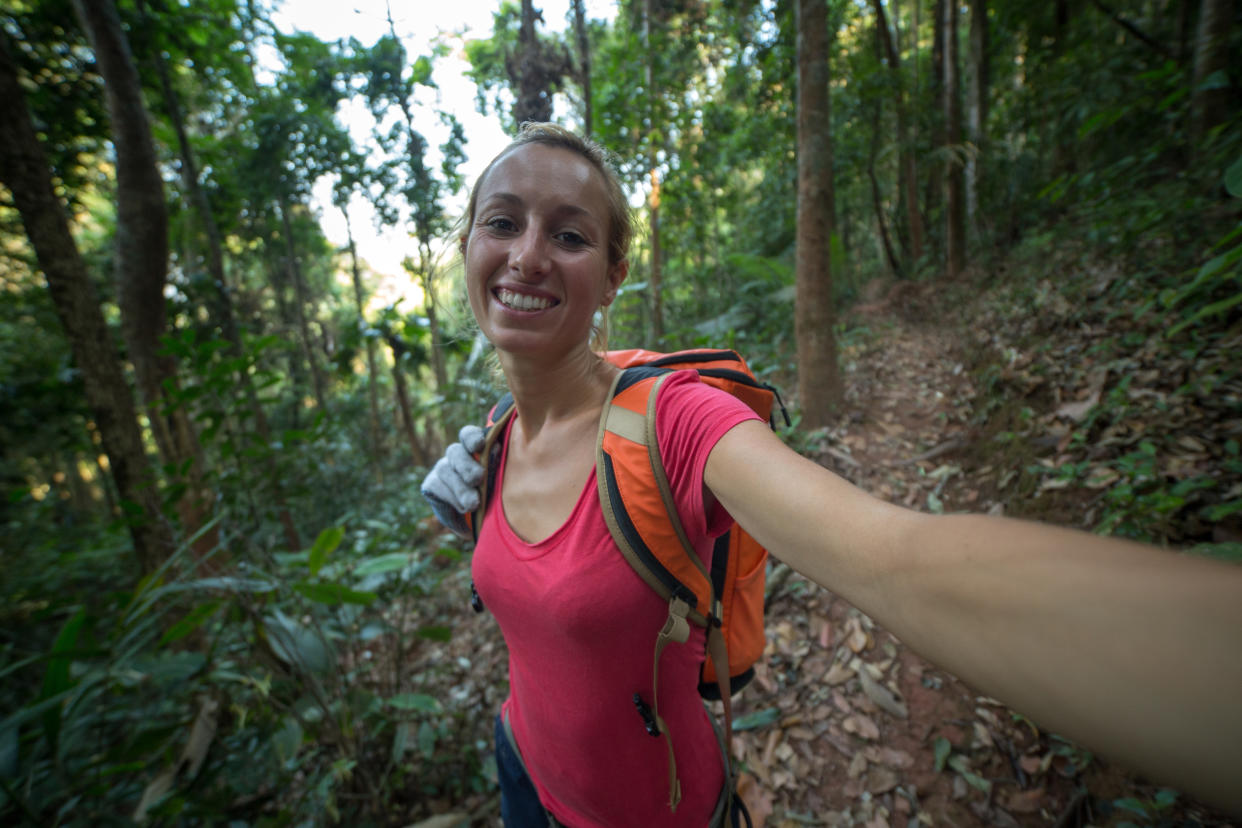 Young healthy woman enjoying hiking on a canopy tour adventure in the rain forest in northern Laos, sunny summer day.