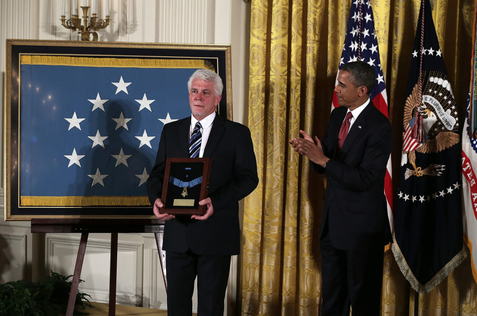 Pres. Obama looks on as Ray Kapaun (L), nephew of U.S. Army Chaplain (Captain) Emil J. Kapaun, holds his uncle’s Medal of Honor for conspicuous gallantry.