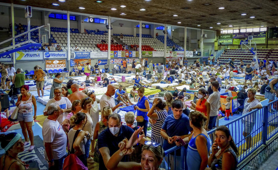 Evacuees sit inside a stadium following their evacuation during a forest fire on the island of Rhodes, Greece, Sunday, July 23, 2023. Some 19,000 people have been evacuated from the Greek island of Rhodes as wildfires continued burning for a sixth day on three fronts, Greek authorities said on Sunday. (Argyris Mantikos/Eurokinissi via AP)