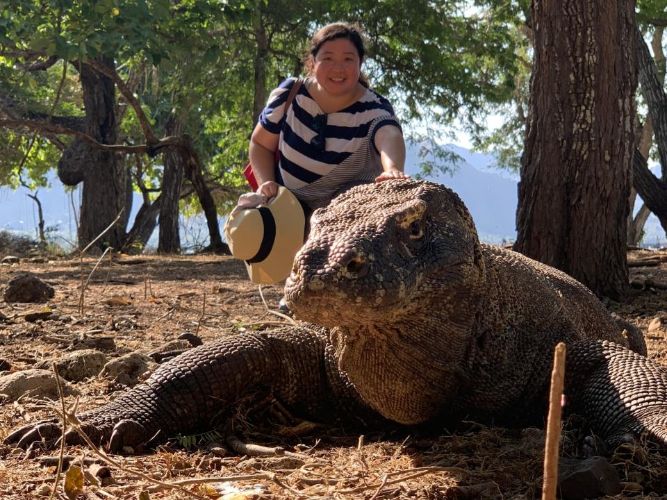 A woman posing with a large Komodo dragon.