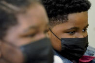 In this Sept. 23, 2021, photo Royal Smart, right, and Roy react while they listen to their mother, Domonique Wilson talks during an interview with the Associated Press in Chicago. Royal Smart remembers every detail about the moment he was handcuffed by police in south Chicago. He remembers the cold March darkness. The feeling of the handcuffs on his wrists. The panic as he was led outside of his house, arms raised, to face dozens of guns pointed at him by police. He was only 8 years old. (AP Photo/Nam Y. Huh)