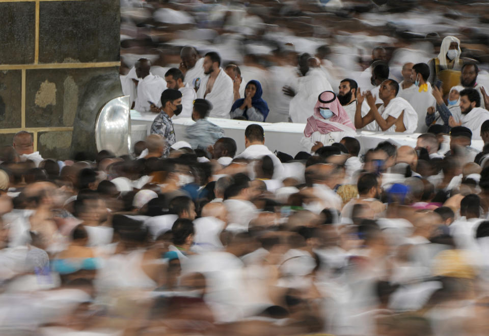 In this photo taken with low shutter speed, Muslim pilgrims pray as others circumambulate around the Kaaba, the cubic building at the Grand Mosque, in Mecca, Saudi Arabia, Wednesday, July 6, 2022. Muslim pilgrims are converging on Saudi Arabia's holy city of Mecca for the largest hajj since the coronavirus pandemic severely curtailed access to one of Islam's five pillars. (AP Photo/Amr Nabil)