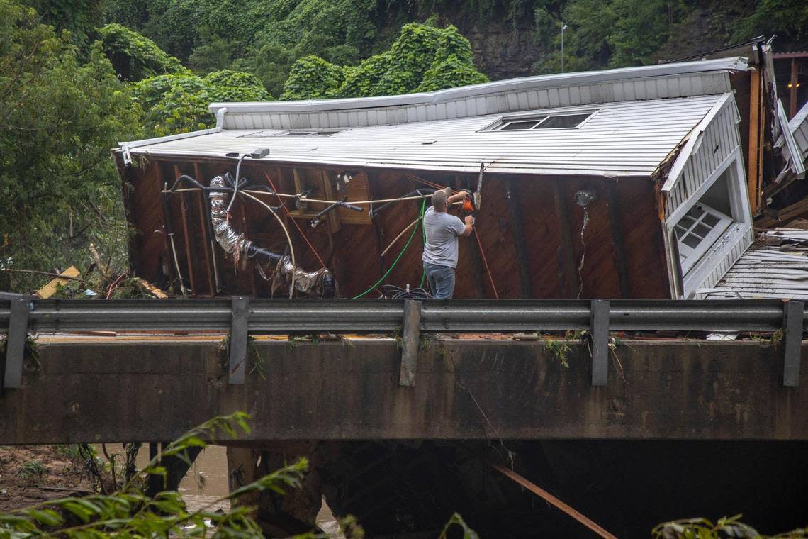 Sammy Gibson uses a chainsaw to cut apart a house that came to rest on a bridge near the Whitesburg Recycling Center in Letcher County, Ky., on Friday, July 29, 2022.