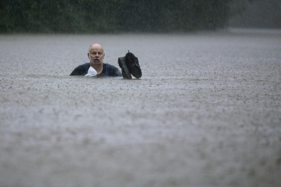 A man wades out through floodwaters caused by heavy rain spawned by Tropical Depression Imelda inundated the area on Thursday, Sept. 19, 2019, in Patton Village, Texas. (Brett Coomer/Houston Chronicle via AP)